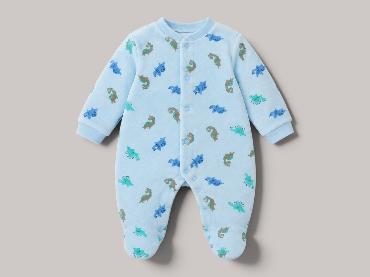 Pijama de bebé NAVIA en color azul claro con estampado de dinosaurios, confeccionado en algodón suave y transpirable.