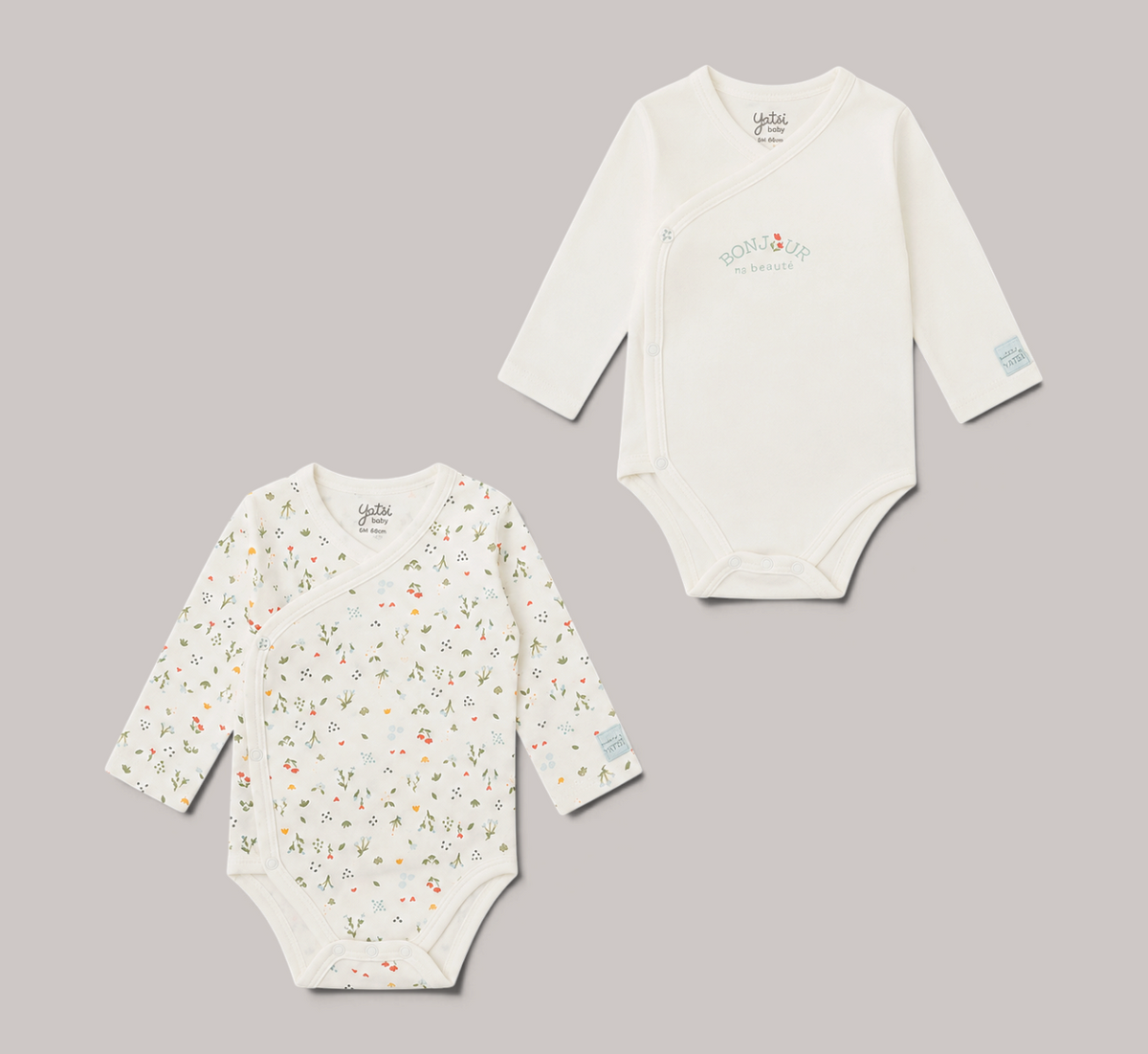 Pack de 2 bodies cruzados NAVIA YATSI BABY, uno blanco con estampado floral y otro con texto, manga larga, algodón.