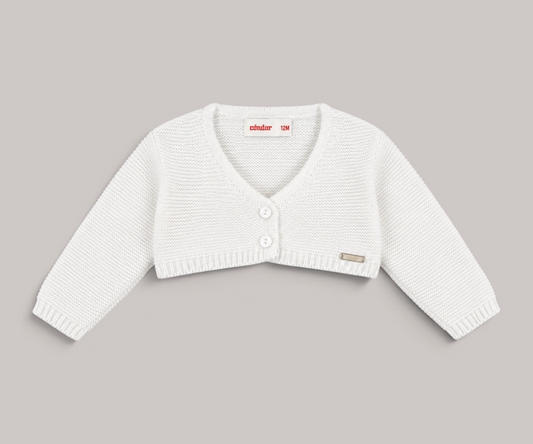 Chaqueta de lana blanca para bebé de NAVIA, punto suave con cierre de botones y detalle de placa metálica.