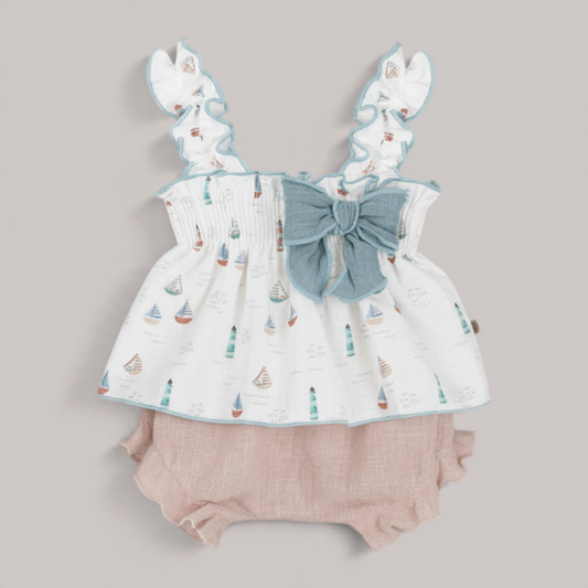 Conjunto NAVIA para bebé niña con blusa de barcos, volantes, lazo azul y braguita de algodón en tono rosa empolvado.