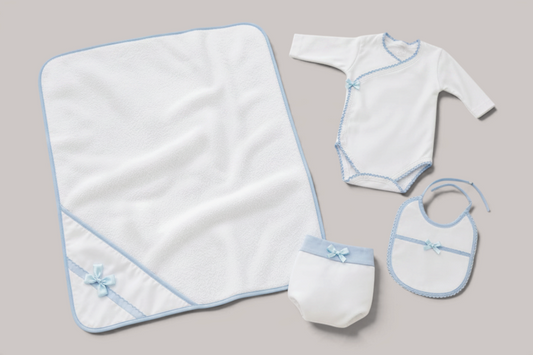 Canastilla de bebé NAVIA con manta, body, cubrepañal y babero de algodón blanco con detalles en azul pastel